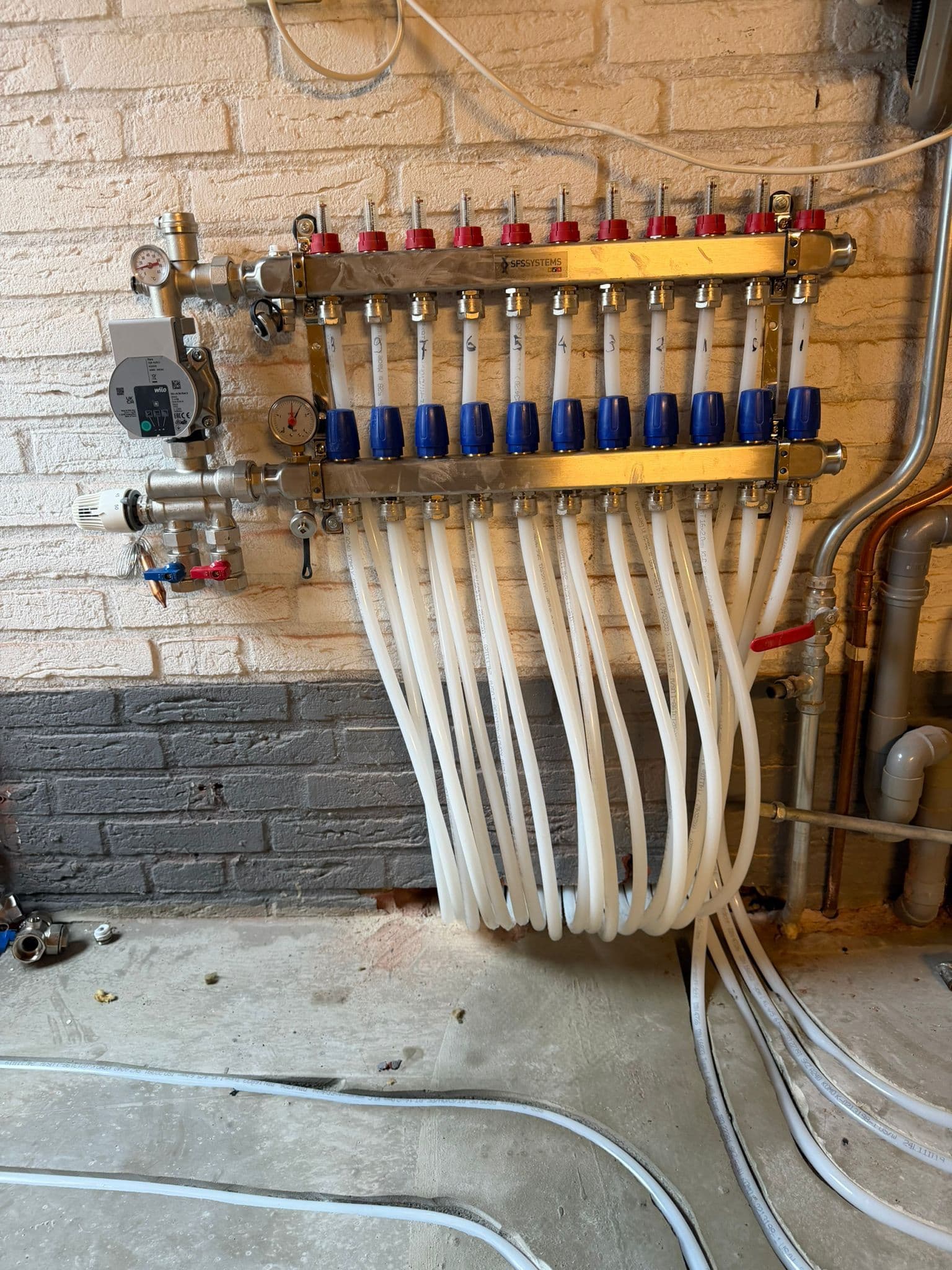 Vloerverwarmingsverdeler met aangesloten groepen aan de wand